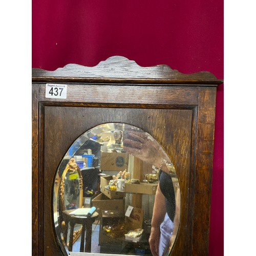 437 - Wall hanging bevelled oval mirror with shelf and cupboard to base in dark Oak. Measures 62 cms tall