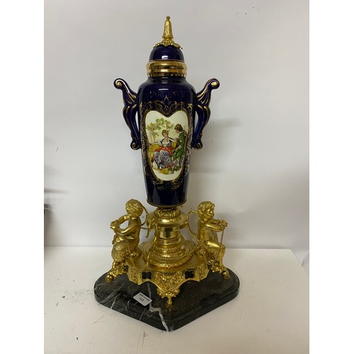 958 - Ornate centrepiece with marble base and gold tone cherubs and cobalt blue urn measuring 58 cms tall
