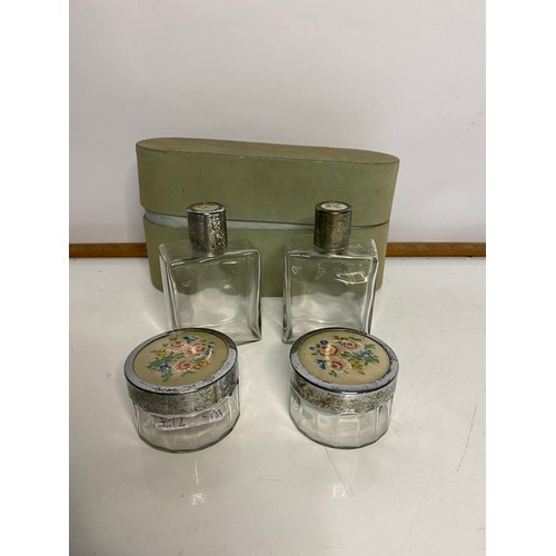 667 - Set of dressing table bottles with embroidery insets to lids, comes with storage box.