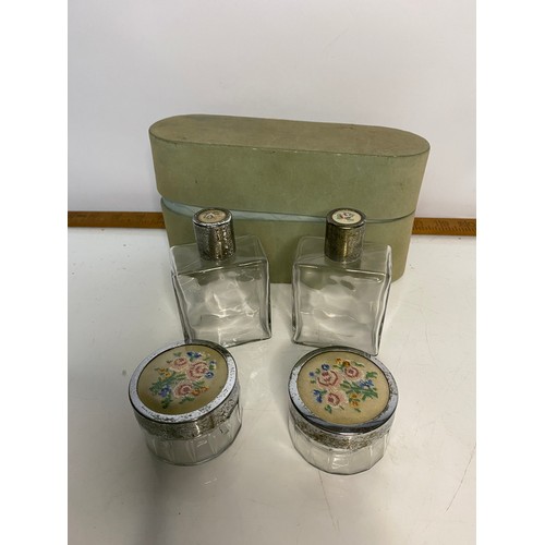 667 - Set of dressing table bottles with embroidery insets to lids, comes with storage box.