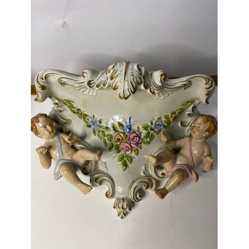 203 - Pair of porcelain cherub wall sconces measuring 28 cms wide x 17 cms deep