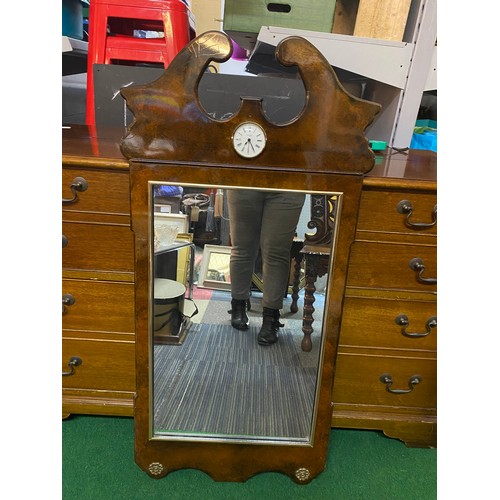 758 - Ornate wall mirror with decorative top housing a Blandford clock measuring 46 x 100 cms tall