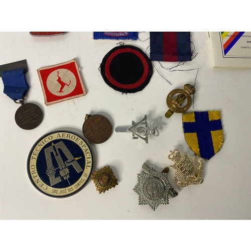 9 - Selection of militaria including cap badges, medals and patches.