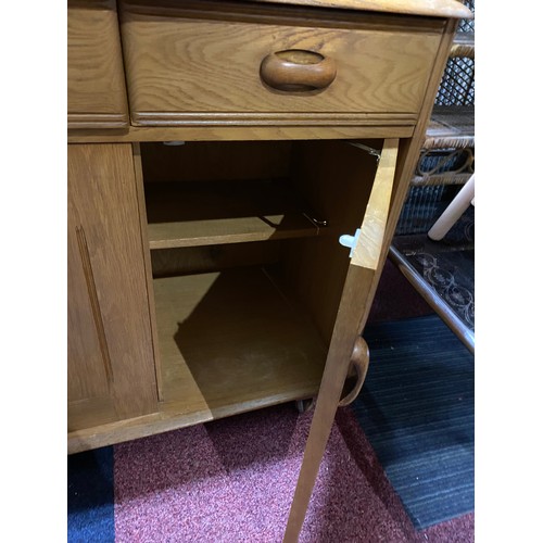 955 - Ercol style light oak sideboard with concertina opening door, 3 drawers and display shelving to top.