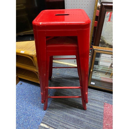 561 - 2 red metal stools, measuring 66 cm tall.