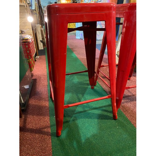 561 - 2 red metal stools, measuring 66 cm tall.