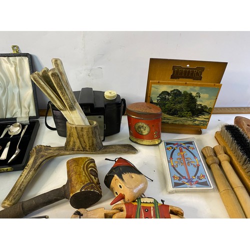 686 - Box of curios and collectables including a carved horn Knife set, tiki pipe and wooden puppet.