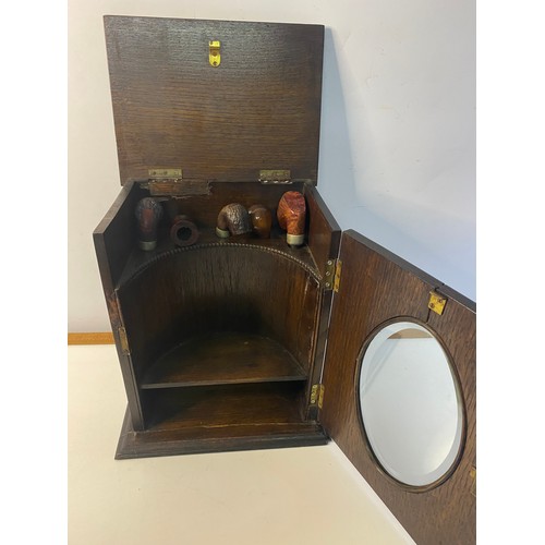 641 - 1920's Oak Smokers cabinet with bevelled glass window with a selection of pipes. 31x25.5cms