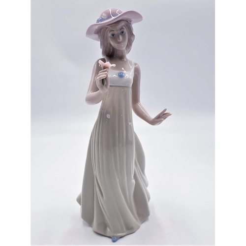 678 - LLADRO (Nao) 25cm CHARACTER FIGURINE OF A YOUNG LADY HOLDING A POSY AND WEARING A PINK FLOPPY HAT