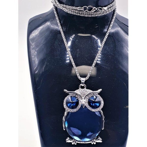 686 - WHITE METAL JEWEL ENCRUSTED Large 5.5cm x 4cm BLUE STONE PENDANT FASHIONED AS AN OWL ON A WHITE META... 