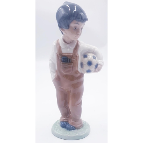 144 - LLADRO (Nao) 18.5cm PORCELAIN CHARACTER FIGURINE OF A YOUNG BOY HOLDING A FOOTBALL 