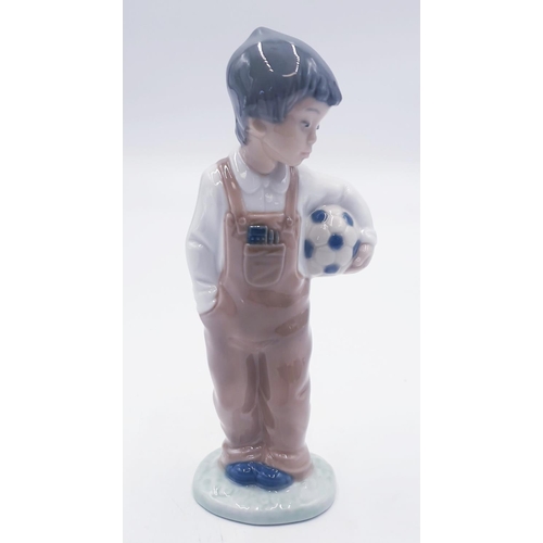 606 - LLADRO (Nao) 18.5cm PORCELAIN CHARACTER FIGURINE OF A YOUNG BOY HOLDING A FOOTBALL 