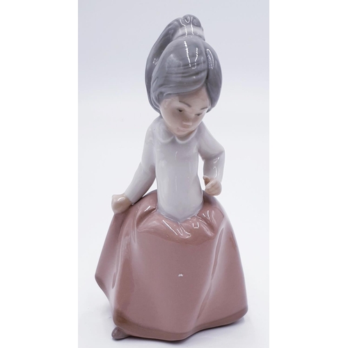 764 - LLADRO (Nao) PORCELAIN 15cm CHARACTER FIGURINE OF A YOUNG GIRL HOLDING HER DRESS