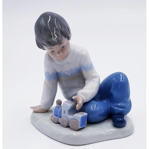 765 - LLADRO (Nao) PORCELAIN 12cm x 12cm CHARACTER FIGURINE OF A YOUNG BOY WITH TOY TRAIN 