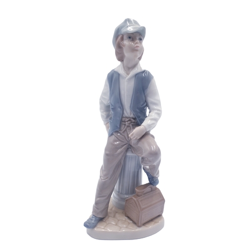 696 - LLADRO (Nao) PORCELAIN Large 24.5cm CHARACTER FIGURINE OF A YOUNG BOY WEARING A CAP ,SITTING ON A WA... 