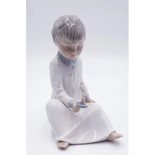 294 - LLADRO (Nao) PORCELAIN 16cm x 13cm CHARACTER FIGURINE OF A YOUNG BOY SITTING DOWN HOLDING A CANDLE 