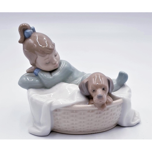 83 - LLADRO (Nao) 12cm x 15cm CHARACTER FIGURINE OF A GIRL SLEEPING With PUPPY IN IT'S BASKET 