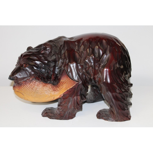 69 - A large carved brown bear with a salmon in mouth. 33cm tall X 50cm long