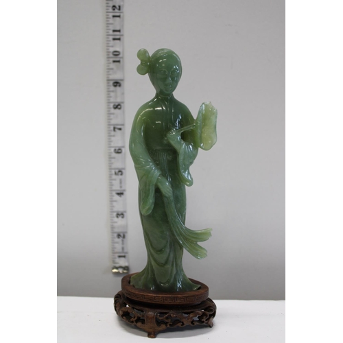 132 - A jadite figure on a wooden stand with slight damage to the figure