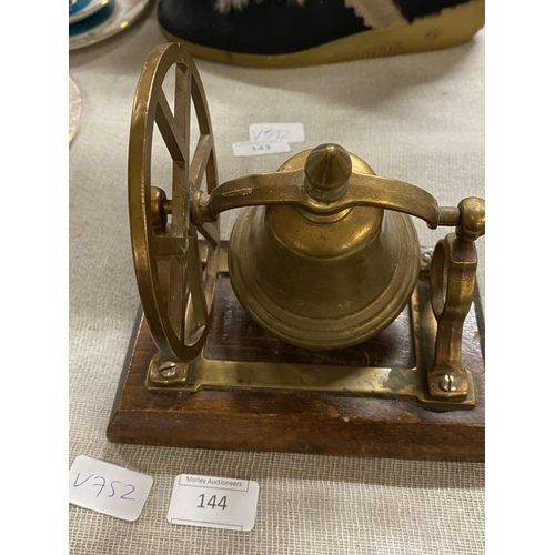 144 - A brass novelty table bell on wooden stand