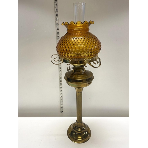 74 - A antique brass based oil lamp with amber glass shade h70cm, shipping unavailable