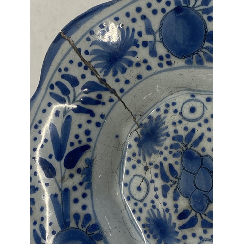 374 - A 17th century delf blue and white lobed dish with fruit decoration (has large crack)