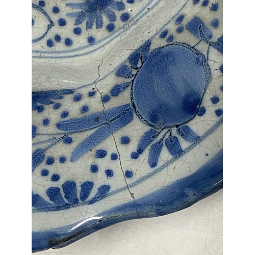 374 - A 17th century delf blue and white lobed dish with fruit decoration (has large crack)