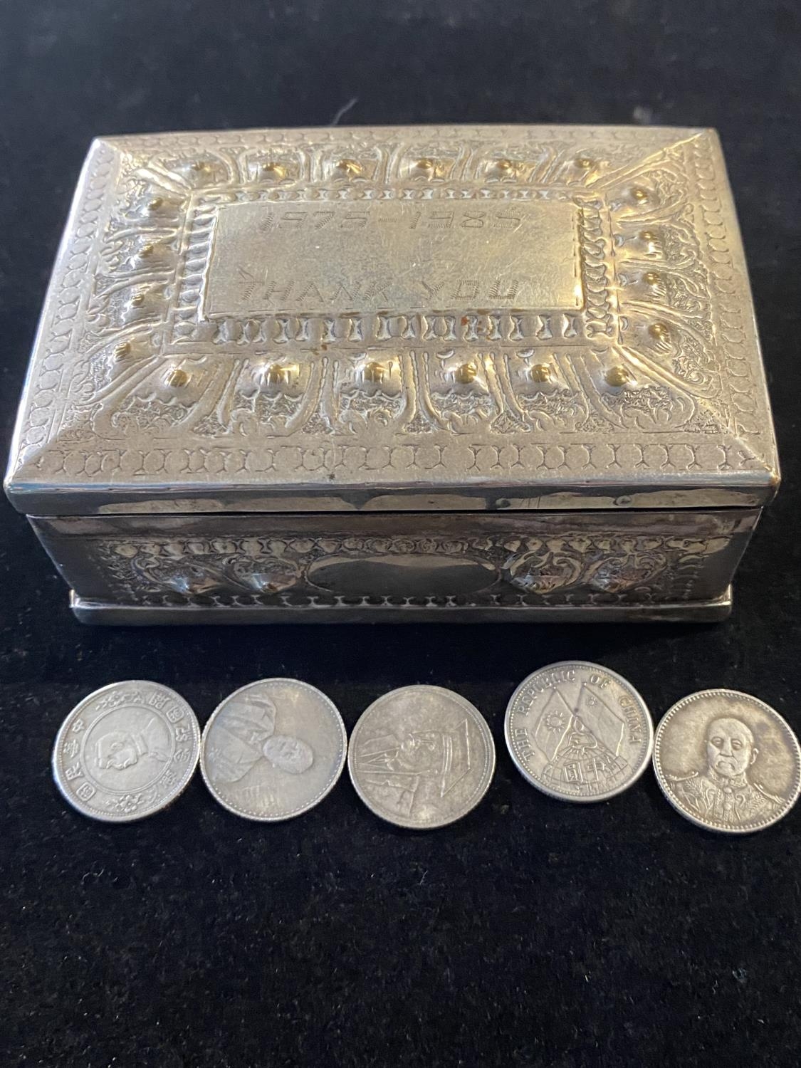 A Chinese white metal box with five Chinese coins