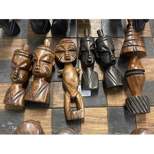 313 - A large hand carved African themed wooden chess board and pieces shipping unavailable