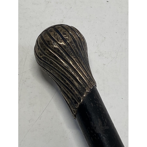 606 - A ebonised walking cane with white metal top