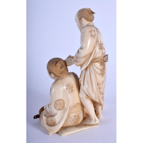 1044 - A 19TH CENTURY JAPANESE MEIJI PERIOD CARVED IVORY OKIMONO modelled as a male picking wax from anothe... 