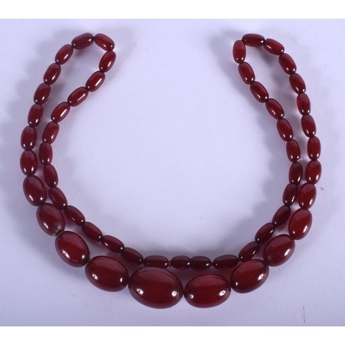 1056 - A 1930S CHERRY AMBER CATALIN TYPE NECKLACE of graduated form. 62 grams. 68 cm long, largest bead 3 c... 