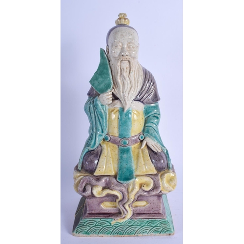 1151 - A 17TH CENTURY CHINESE BISCUIT GLAZED SANCAI FIGURE OF A SCHOLAR Kangxi, modelled holding a fan upon... 