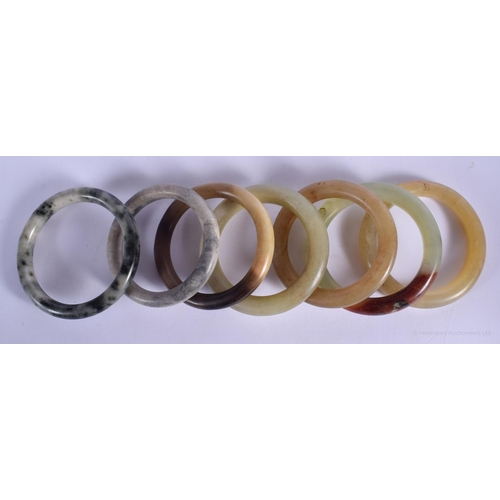 1154 - SEVEN CHINESE QING DYNASTY JADE & HARDSTONE BANGLES in various forms and sizes. 8.5 cm diameter. (7)