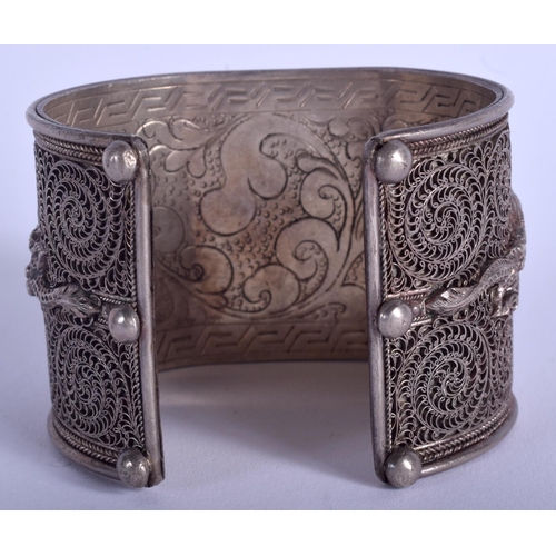 1947 - AN ANTIQUE TIBETAN SILVER AND JADEITE BUDDHISTIC BANGLE. 106 grams.