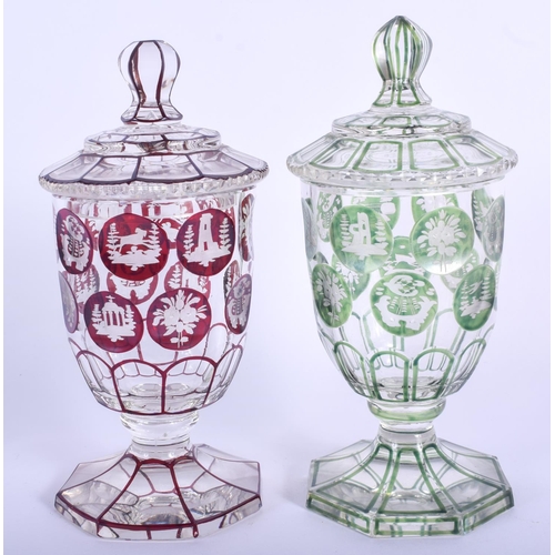 23 - A PAIR OF BOHEMIAN GLASS JARS AND COVERS decorated with animals and landscapes. 17 cm high.