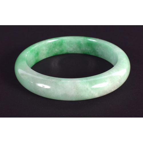 1236 - A CHINESE CARVED JADEITE BANGLE 20th Century. 7.25 cm wide.