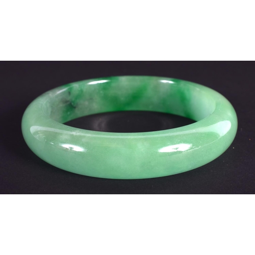 1264 - A CHINESE CARVED GREEN JADEITE BANGLE 20th Century. 7 cm diameter.