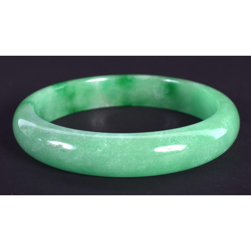 1275 - A CHINESE CARVED GREEN JADEITE BANGLE 20th Century. 7 cm diameter.