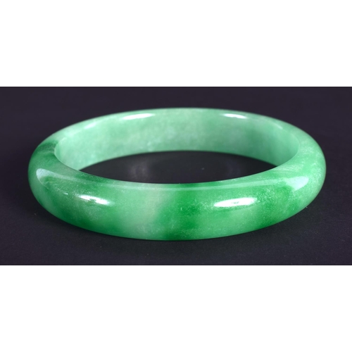 1275 - A CHINESE CARVED GREEN JADEITE BANGLE 20th Century. 7 cm diameter.