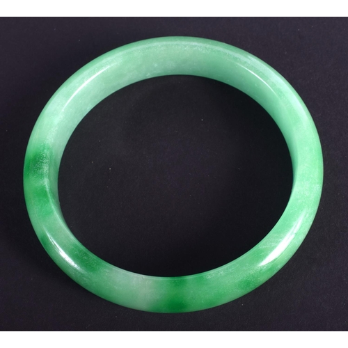 1275 - A CHINESE CARVED GREEN JADEITE BANGLE 20th Century. 7 cm diameter.