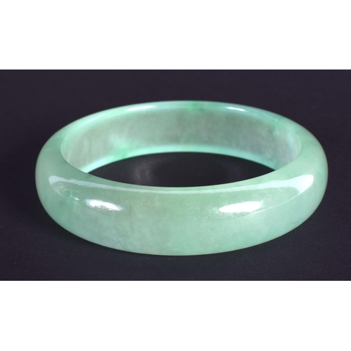 1299 - A CHINESE CARVED JADEITE BANGLE 20th Century. 7.25 cm wide.