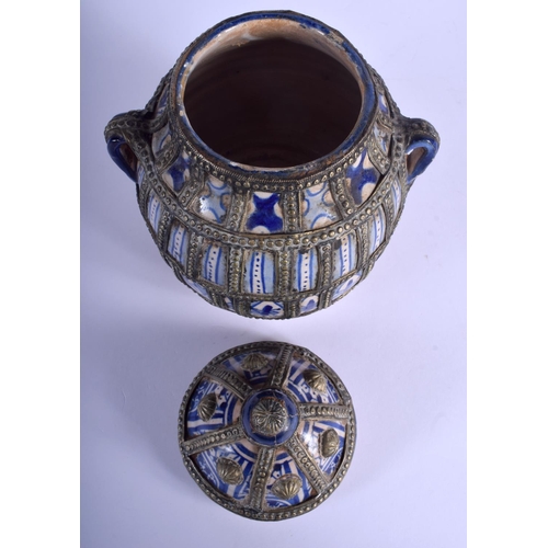 152 - A MIDDLE EASTERN FAIENCE JAR AND COVER with white metal overlay. 26 cm x 16 cm.