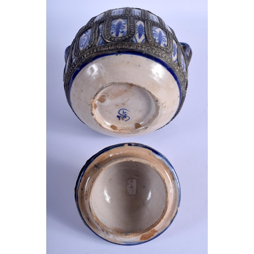 152 - A MIDDLE EASTERN FAIENCE JAR AND COVER with white metal overlay. 26 cm x 16 cm.