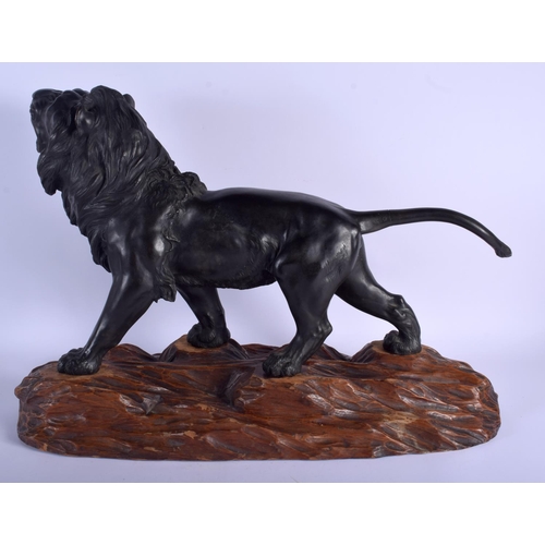 1601 - A 19TH CENTURY JAPANESE MEIJI PERIOD BRONZE OKIMONO modelled as a roaming lion upon a wooden plinth.... 