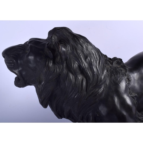 1601 - A 19TH CENTURY JAPANESE MEIJI PERIOD BRONZE OKIMONO modelled as a roaming lion upon a wooden plinth.... 