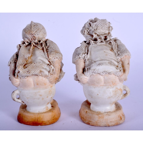 184 - A RARE PAIR OF ANTIQUE GERMAN PORCELAIN FIGURES modelled defecating into mugs. 7.5 cm high.