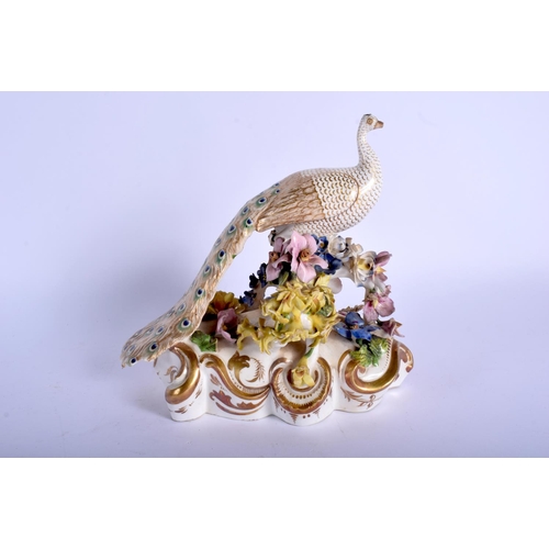 215 - Derby figure of a peacock with floral encrusted base. 15Cm high