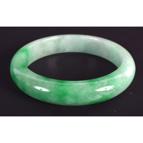 1236 - A CHINESE CARVED JADEITE BANGLE 20th Century. 7.25 cm wide.