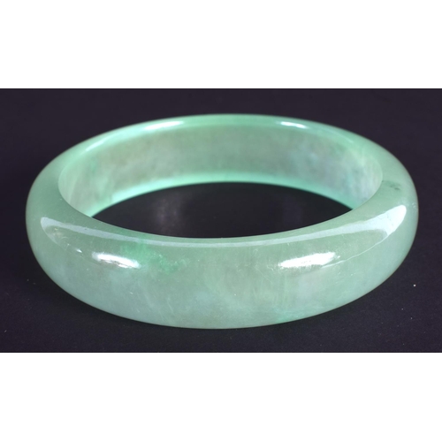 1299 - A CHINESE CARVED JADEITE BANGLE 20th Century. 7.25 cm wide.